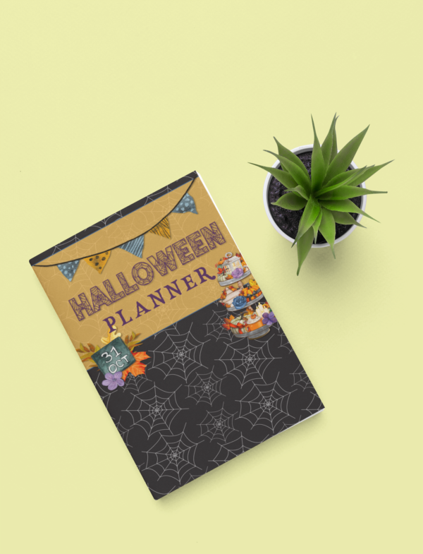 Closed Halloween planner on a yellow surface with a plant