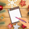 wood table with stars and snowflakes show with lined paper with a hand holding a pen