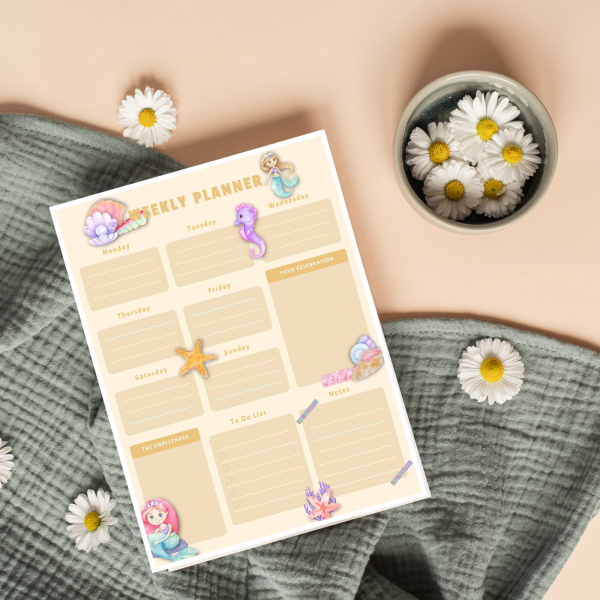 orange background green cloth daisies with watercolor mermaid weekly planner printed out laying with mermaids and seashells