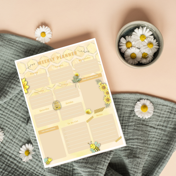 green blanket with daisys in a bowl and on the blanket with the weekly planner sheet ready to be used showing all the boxes for bullet journally.