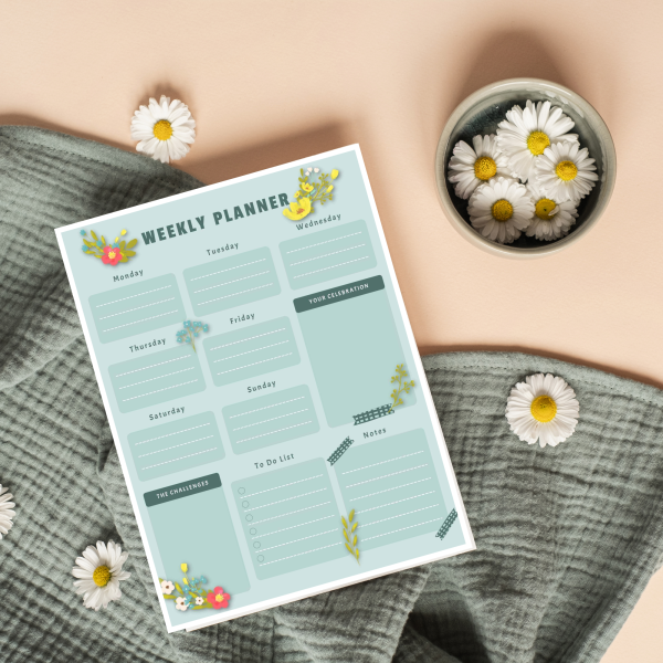 orange background green cloth, daisy with wildflower weekly planner with green on green squares and wildflowers of pink, blue, yellow, and white with greener on the weekly sheet