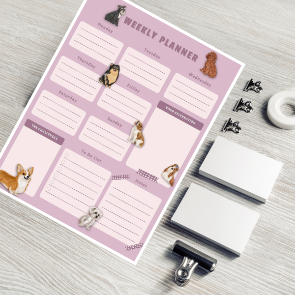 on a desk with clips and tape is a purple background dog weekly planner with many styles of dogs
