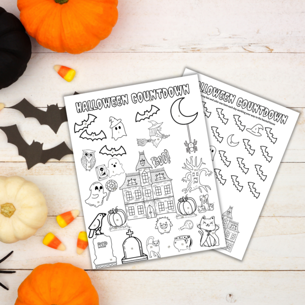 white washed table with pumpkins, candy corn, cut out bats and two papers of countdown halloween printable