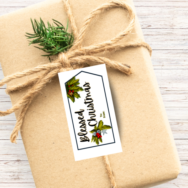 wood background, Kraft paper wrapped box with twine and a spring of evergreen, with a tag shaped tag with Blessed Christmas in black with evergreen in the corners with bells and stars