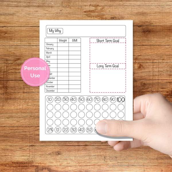 medium brown table top, person hold paper, pink bubble that says personal use, showing the red version of the yearly weight tracker planner sheet with weight & BMI for each month, WHY, short and long term goals, percentage tracker