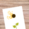 shows brown table with picture of handprints on the yellow sunflower.