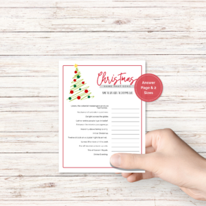 wood background, with a hand holding the christmas party game with tree with red border, has a red dot that says answer page and 2 sizes.