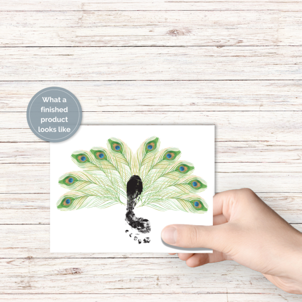 wood background, shows hand holding printable in the air with peacock feathers of green, yellow, and blue eyes, and footprint in the middle. Grey circle says What a finished product looks like