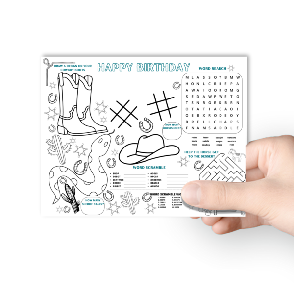 white backdrop with a hand holding the birthday activity placemat in western theme that shows cowboy boots, cowgirl hat, cactus, counting, maze, unscramble, word search, tic tac toe,