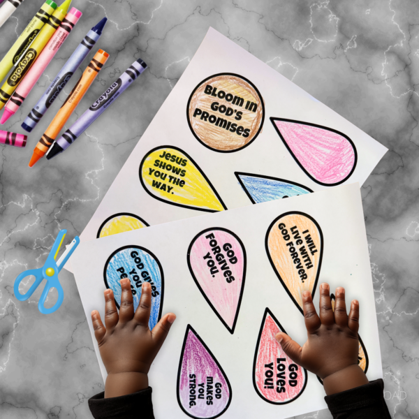 grey marble table, crayons, and scissors, shows hands on colored promise petals ready to cut them out to assemble a diy bible craft materials,