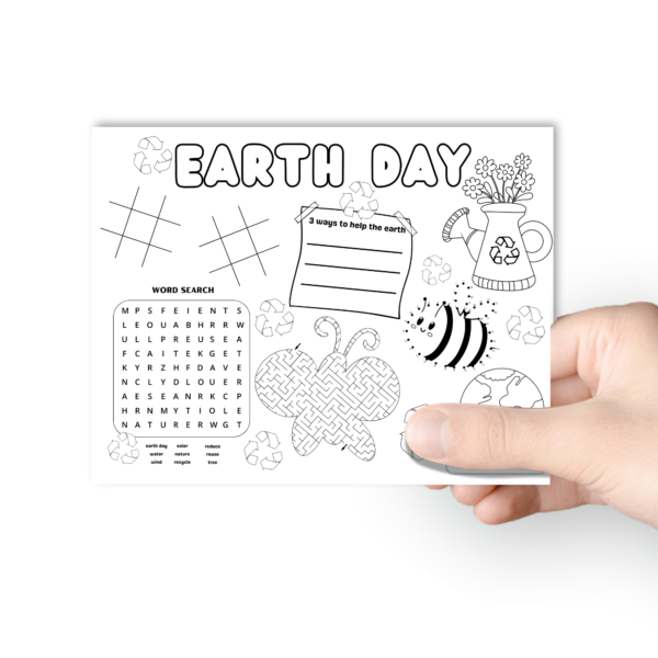 white background, shows a hand holding the table mat . has coloring of earth, flowers, recycling signs, dot to dot bee, maze butterfly, word search, and tic tac toe on the placemat.