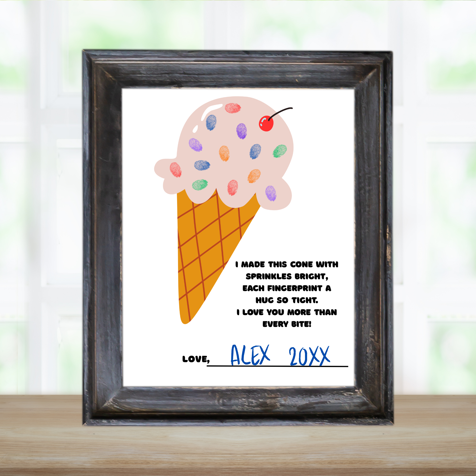 black frame on table that is holding a finished fingerprint craft project. shows a poem, ice cream Cone with fingerprint sprinkles and love and a name and date.